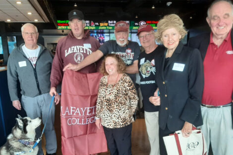 A group of alumni stand with a Lafayette flag.