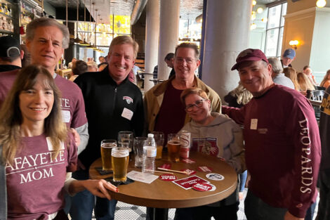 A group of alumni gather at a table at a bar.