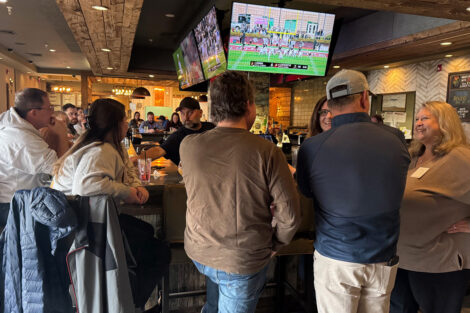 Alumni are standing at a bar.