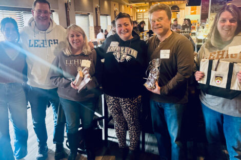 Alumni stand and smile at a camera at a restaurant