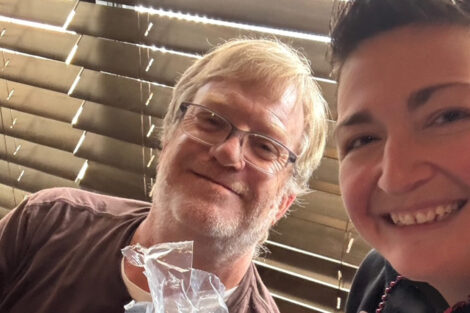 Two alumni smile at the camera.