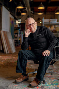 Ed Kerns is wearing all black and is seated with his hand on his kneee